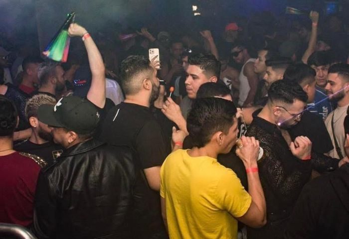 True Colors Bar in New York: A lively crowd of gay men dance at a popular gay bar in NYC. Rainbow flag and vibrant nightlife scene.