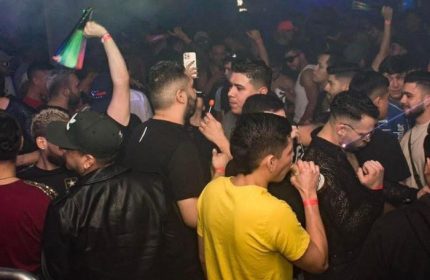 True Colors Bar in New York: A lively crowd of gay men dance at a popular gay bar in NYC. Rainbow flag and vibrant nightlife scene.