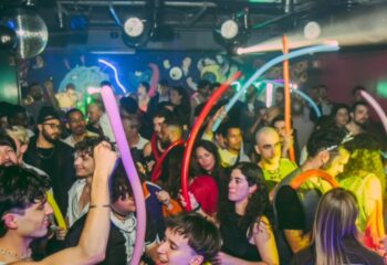 Gay men at Trumps Lisbon, a vibrant gay club in Portugal. Partygoers with balloons dance under disco lights. Gay travel nightlife scene.