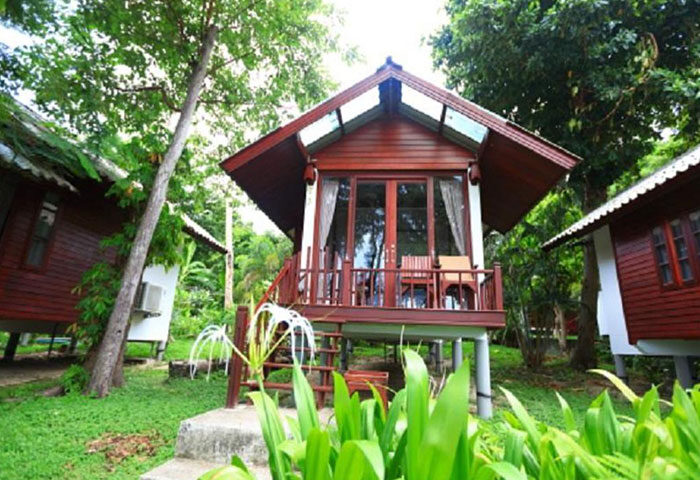 Tubtim Resort Koh Samet beachfront hotel. Wooden bungalow with balcony, steps, and tropical foliage. A popular gay-friendly destination.