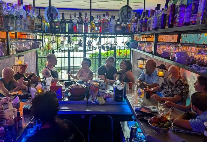Inside Tunnel Gay Bar, Puerto Vallarta. Patrons at the bar with a bartender. Bottles line the shelves. Popular gay travel destination.