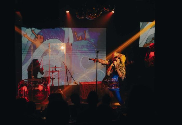 Live music at Tunnel Gay Bar in Puerto Vallarta. Singer performs on stage with band, lights, and disco balls. Gay nightlife travel.