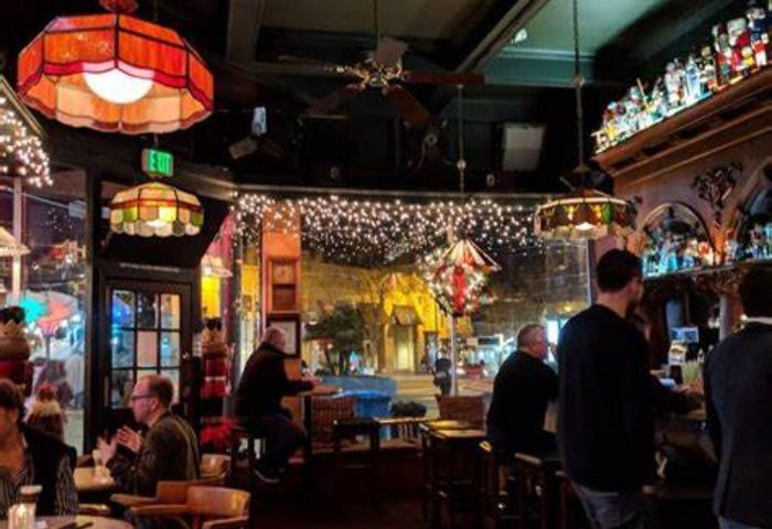 Twin Peaks Tavern, San Francisco's iconic gay bar. Interior view with patrons, vintage lamps, and festive lights. A welcoming, historic space.