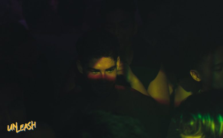 Man at UNLEASH, top gay event in Singapore. Go-go dancers and influencer dancers create a vibrant nightlife experience. Dark, intimate setting.