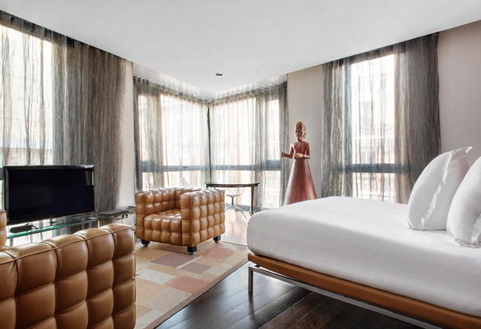 Urban Hotel Madrid room. Modern design, brown leather chairs, TV, large windows. Near Chueca, popular for gay honeymoon trips.