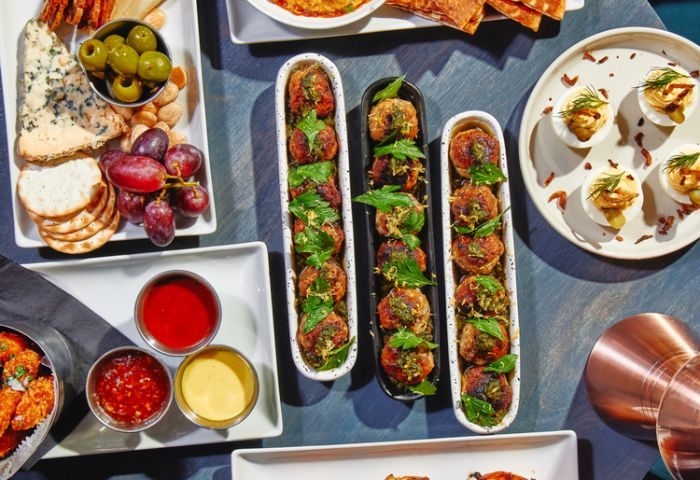 VERS venue in New York food spread. Appetizers include meatballs, deviled eggs, cheese, crackers, fruit, and dipping sauces. Gay travel.