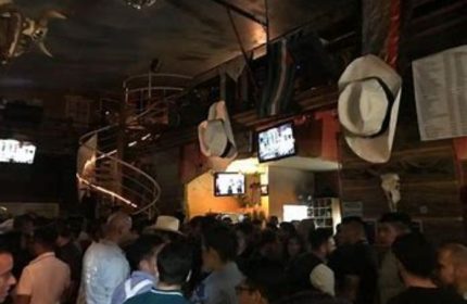 Inside Vaqueros Gay Bar in Mexico, a crowded space with cowboy hats hanging from the ceiling & a spiral staircase, for gay men travel advice.