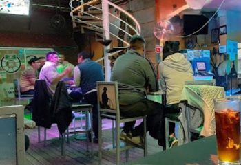 Inside Vaqueros Gay Bar in Mexico, patrons sit at the bar. Unique chair art. Gay travel advice. Nightlife.