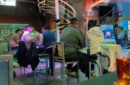 Inside Vaqueros Gay Bar in Mexico, patrons sit at the bar. Unique chair art. Gay travel advice. Nightlife.