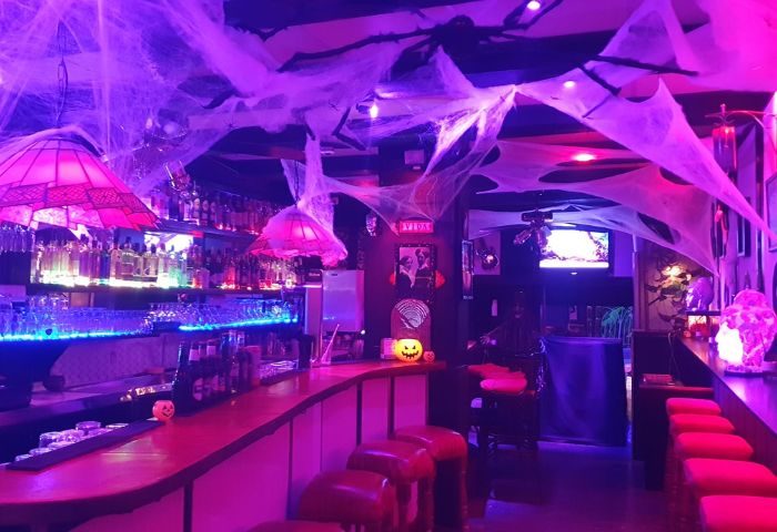 Vida Bar, a gay bar in Torremolinos, Spain, decorated for Halloween. Purple and pink lighting, spiderwebs, and jack-o'-lanterns.