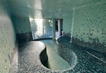 Vista Grande Resort for Gay Men steam room in Palm Springs. Aqua mosaic tiles cover curved benches, walls, & ceiling. Glass block window.