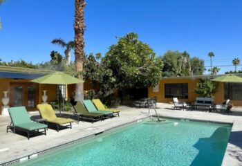 Vista Grande Resort for Gay Men in Palm Springs: Poolside view with lounge chairs, umbrella, and clear blue water under a sunny sky.
