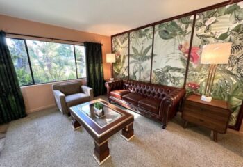 Vista Grande Resort for Gay Men living room with leather sofa, tropical wallpaper, and view of Palm Springs. Gay travel lodging.
