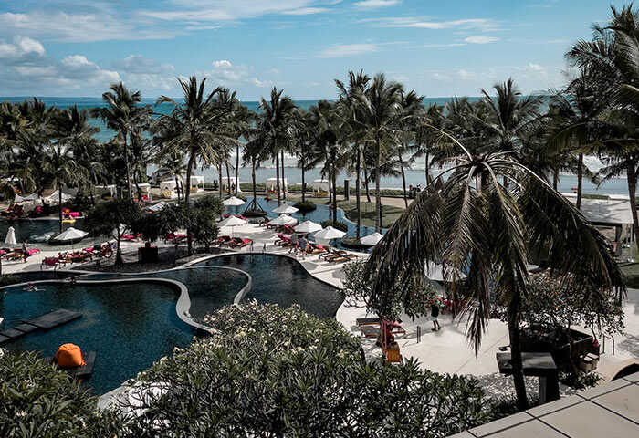 W Bali Seminyak beachfront resort view. Palm trees, pools, and ocean. Gay-friendly hotel near gay bars in Bali, Indonesia.