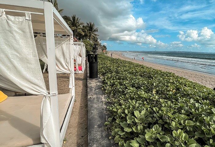 W Bali Seminyak beachfront view. Beach cabanas, sand, ocean, and sky. Top gay honeymoon hotel in Bali.