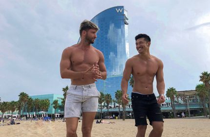 Gay couple at W Barcelona, most booked luxury hotel for honeymoon. Two shirtless men on the beach in front of the W Hotel in Barcelona.