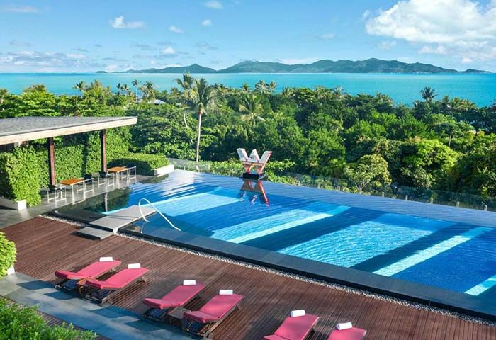 W Koh Samui gay-friendly hotel infinity pool. Tropical island view, lounge chairs. A luxurious destination for gay travel in Thailand.