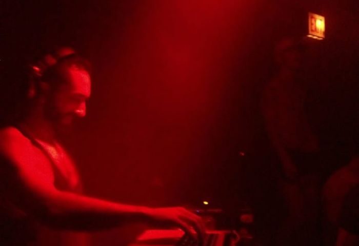 DJ at Wang's Gay Bar in Chicago. Red lighting illuminates the scene. Nightlife for gay men's travel advice. Chicago's gay scene.