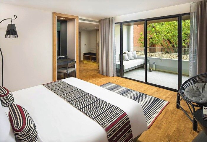 Gay travel: X2 Chiang Mai Riverside Resort suite. Balcony, daybed, chic decor. Luxury hotel for gay men's wellness retreat in Thailand.