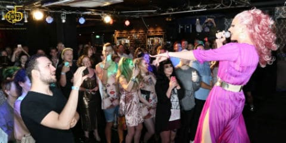 West 5 Gay Bar crowd enjoying a drag queen performance. People are taking photos, enjoying the show in a lively atmosphere. Nightlife scene.
