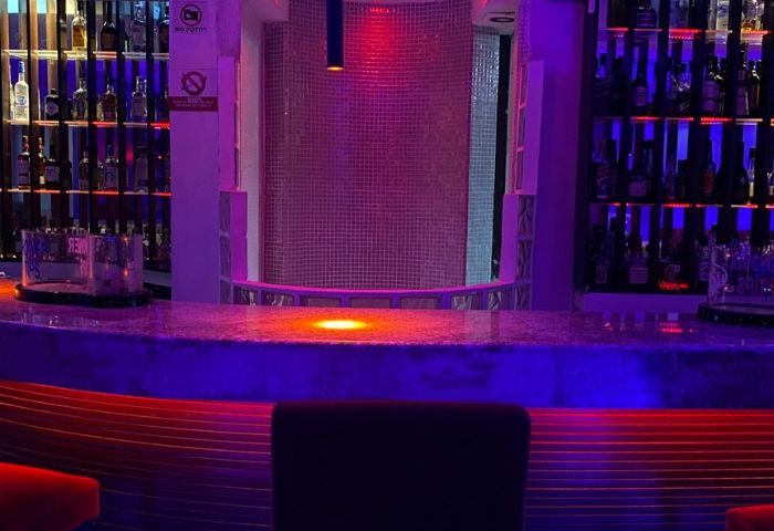 Wet gay bar in Puerto Vallarta, Mexico. Bar counter with bottles, colorful lights, & a unique tiled backdrop for gay men travelers.