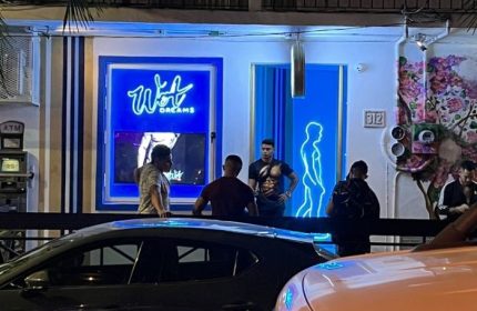 Night view of Wet Dreams gay bar in Puerto Vallarta. Men gather outside the bar with blue neon sign and male silhouette. Gay travel.