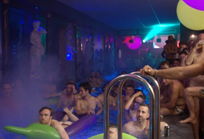 Gay men at Wet on Wellington bathhouse in Melbourne. A group of shirtless men in a pool with inflatable toys, statues, and party lights.