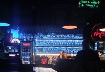Why Not Cafe and Bar Budapest interior. Bar with glasses, drinks, and neon lights. Gay travel advice for Budapest's vibrant nightlife.