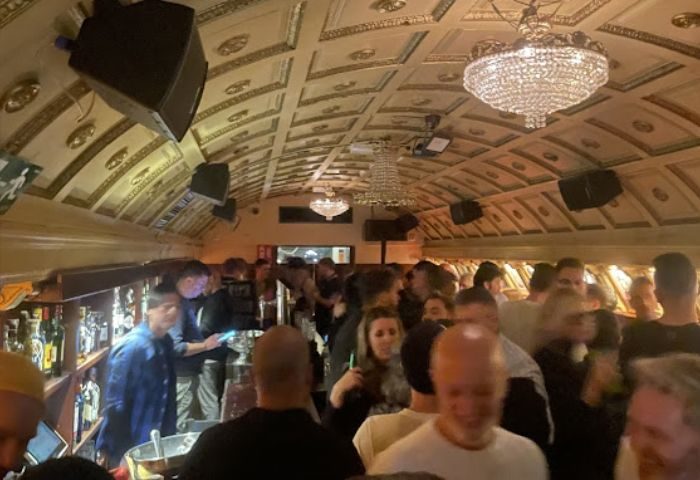 Busy Why Not? gay bar in Madrid. Chandeliers hang from the ornate ceiling above a crowd of men enjoying drinks at this popular gay bar.