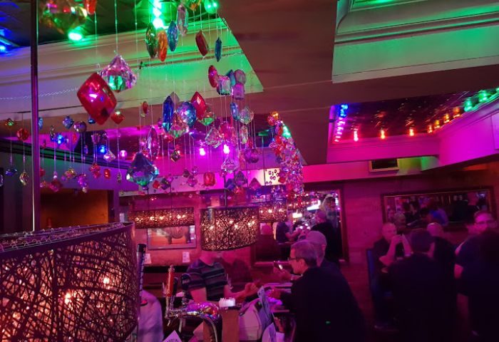 Interior of Woody's and Sailor gay bar in Toronto. Colorful lights, patrons at the bar, and hanging decorations. Gay travel.