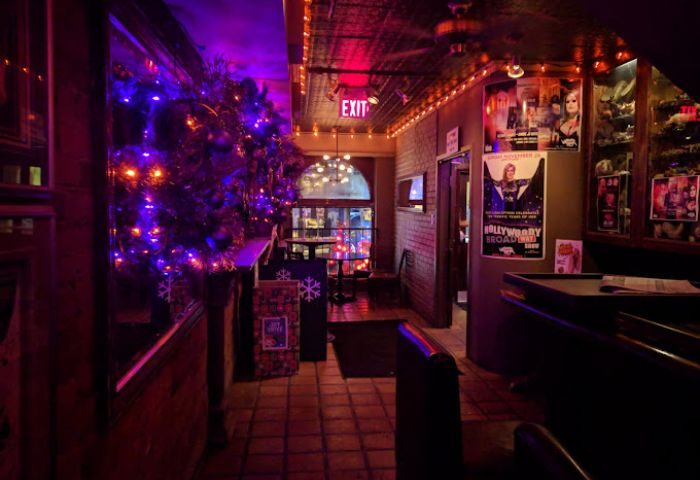 Interior of Woody's and Sailor gay bar in Toronto. Christmas decorations, posters, and dim lighting create a cozy atmosphere.