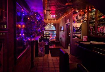Interior of Woody's and Sailor gay bar in Toronto. Christmas decorations, posters, and dim lighting create a cozy atmosphere.
