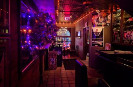 Interior of Woody's and Sailor gay bar in Toronto. Christmas decorations, posters, and dim lighting create a cozy atmosphere.