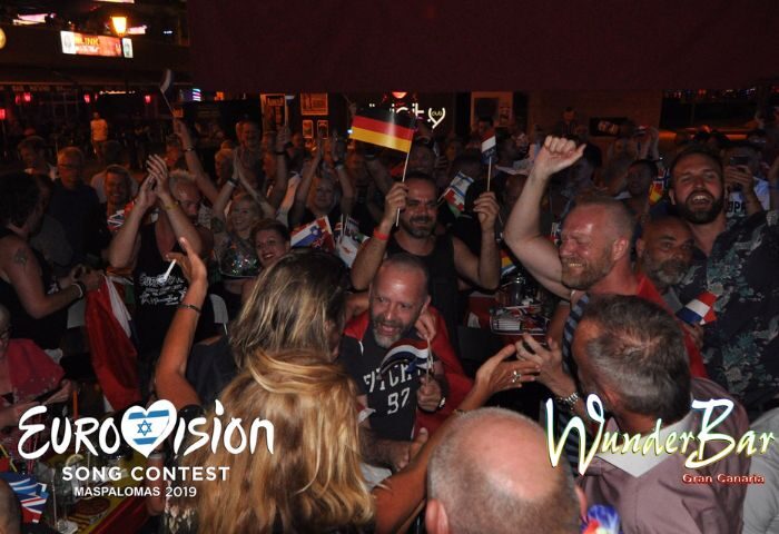 Gay bar WunderBar in Gran Canaria during Eurovision. Crowd cheers, waving flags. Gay travel advice for Maspalomas.