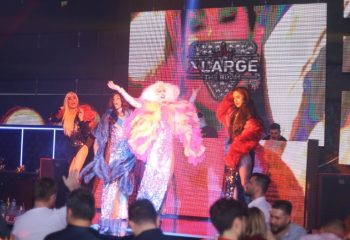 Drag queens perform at XLarge Club Istanbul, a popular gay nightlife spot. The stage is lit with colorful lights, and the audience enjoys the show.