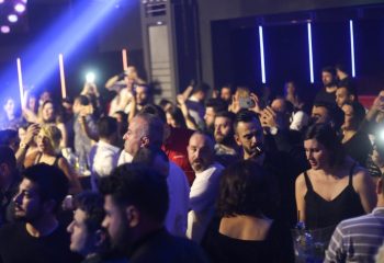 Crowded X Large Club Istanbul scene. People dancing, taking photos, and enjoying the gay nightlife scene. Blue lighting.