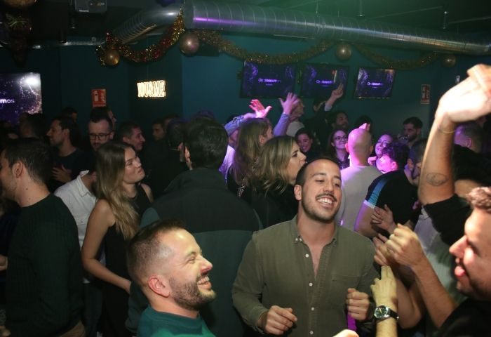 Crowded YOUME Gay Bar in Madrid. People dancing, laughing, and enjoying the vibrant nightlife. Gay travel advice, nightlife, Madrid, Spain.