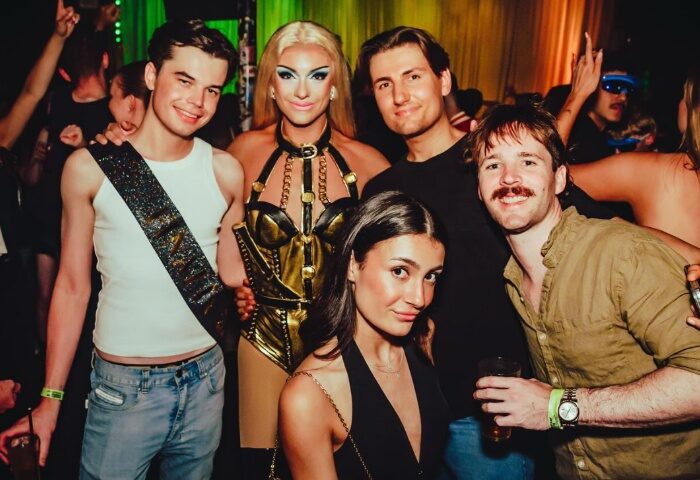 Melbourne's Yah Yah's gay travel scene: Group of friends posing with a drag queen in a gold corset at a party. Nightlife fun.