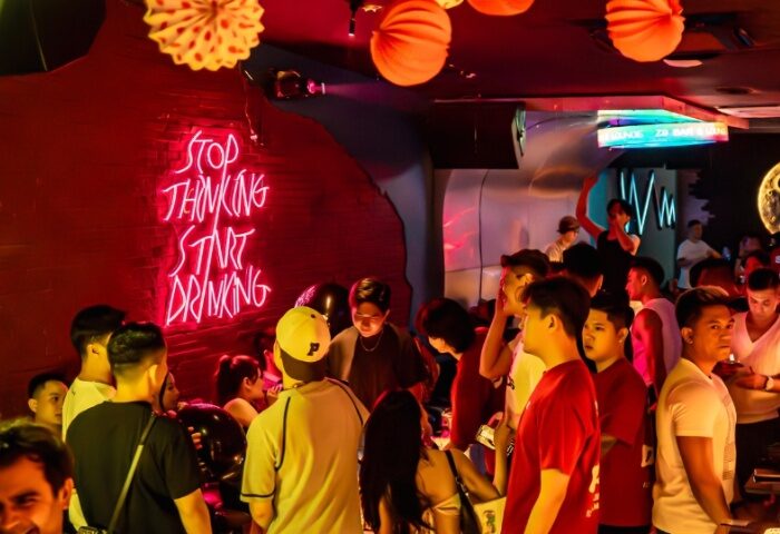 Z9 Bar, Ho Chi Minh City: Gay nightlife scene with a crowd of men. Neon sign reads Stop thinking, start drinking. Red lighting, party vibe.