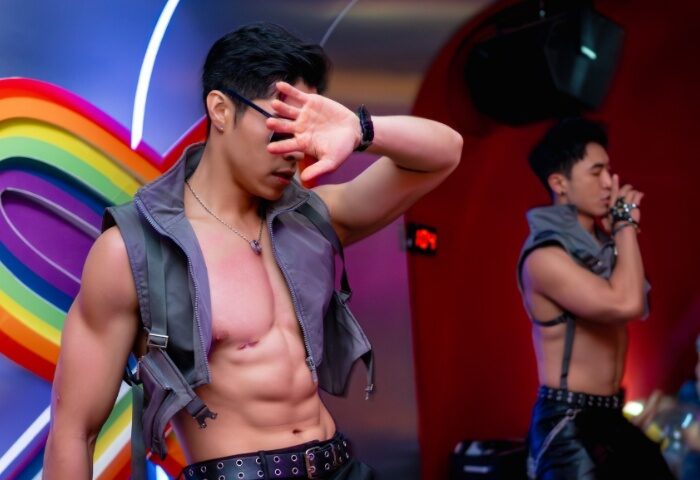 Z9 Bar Ho Chi Minh: Two shirtless, muscular Asian men dance at a gay bar. One covers his face, the other wears a harness. Gay travel advice.