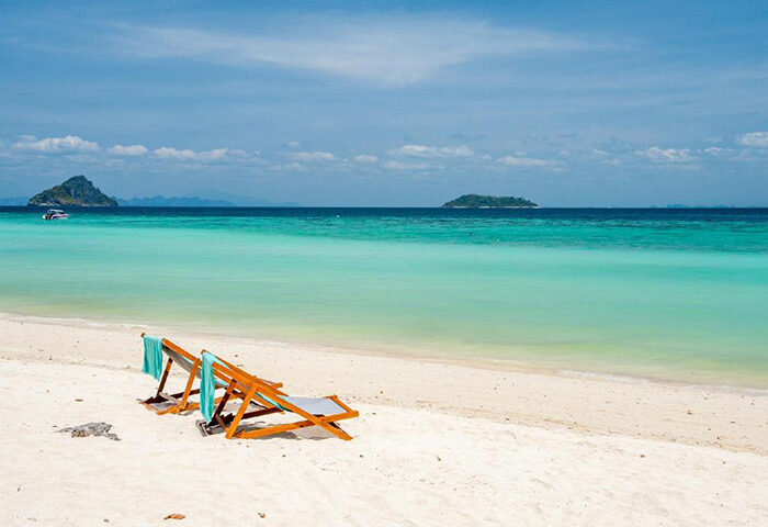 Zeavola Hotel beachfront view in Phi Phi. Two chairs on white sand, turquoise water. Gay travel luxury resort.