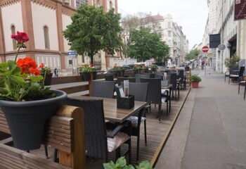Augenblick Vienna outdoor seating area. Tables and chairs line the sidewalk. Gay travel advice for dining in Vienna. augenblick-vienna.jpg