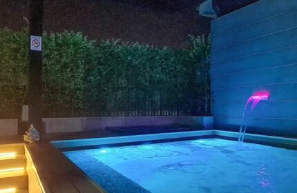 Krubb Bangkok pool. Outdoor jacuzzi with blue lighting, waterfall feature, and lush greenery. Gay travel advice in Bangkok, Thailand.