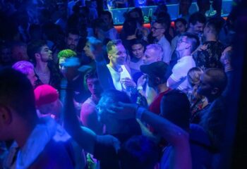 Crowded dance floor at Club TerMIX, a gay club. Men are dancing under blue lights. Gay nightlife travel advice.