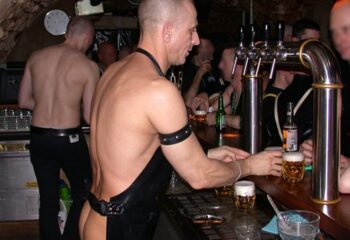 Full Metal Paris: Gay bar scene featuring a bartender in leather attire serving beer. Gay travel advice for nightlife in Paris.