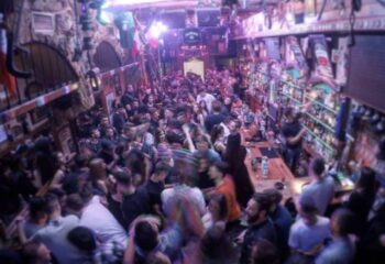 Crowded Murphy's Bar interior. Gay travel advice: Irish pub, packed with people, bar on the right, stone walls, lively atmosphere.
