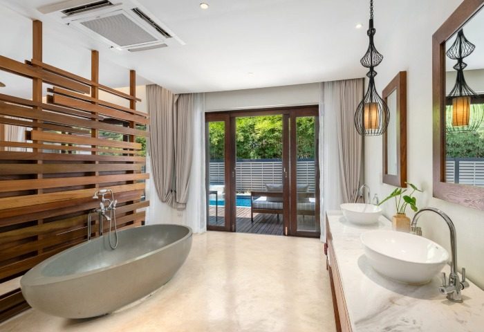 SAii Koh Samui Villa's bathroom. Modern design with soaking tub, double sinks, and outdoor access. Luxury gay travel accommodation.