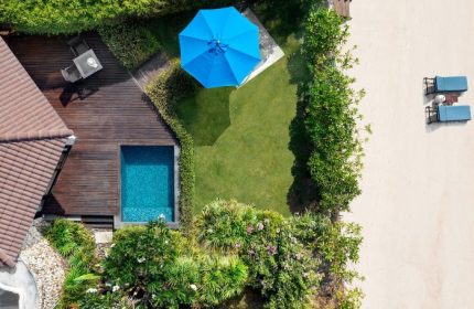 Aerial view of SAii Koh Samui Villas room 0084. Features a private pool, wooden deck, blue umbrella, lush garden, and beach access for gay travelers.
