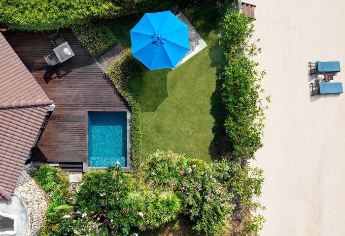 Aerial view of SAii Koh Samui Villas room 0084. Features a private pool, wooden deck, blue umbrella, lush garden, and beach access for gay travelers.