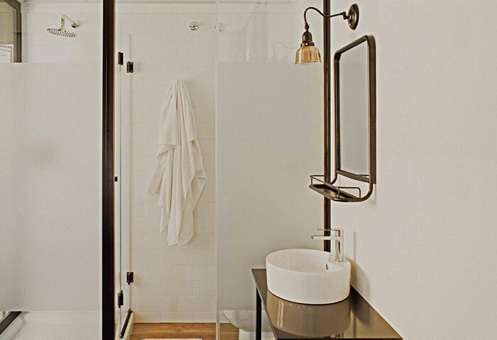 Room007 Chueca Hostel's private bathroom in Madrid. Modern design with shower, sink, mirror, and towel. A top-booked gay hostel choice.